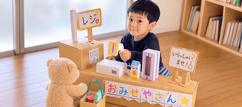 ダンボールでできたお店でお店屋さんごっこをして遊ぶ男の子