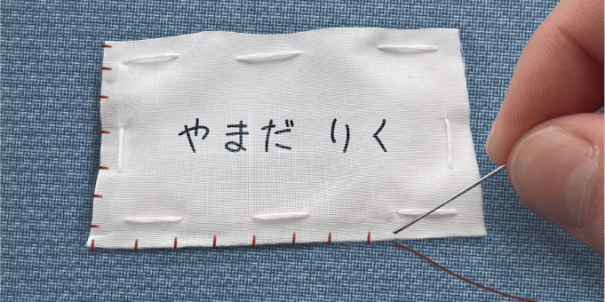 ゼッケンを手縫いで縫い付けている様子